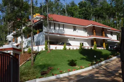 a white house with a red roof and a yard at Ibbanicadu Estate Homestay in Madikeri