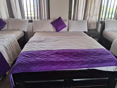 a bed in a room with purple sheets and pillows at Royal homes a3 in Kushālnagar