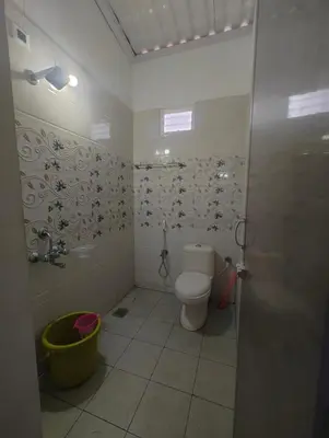 a bathroom with a toilet and a bucket in it at JP Residency, near to Isha, Adhiyogi & Karunya in Alāndurai