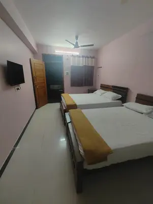 a room with three beds and a television in it at JP Residency, near to Isha, Adhiyogi & Karunya in Alāndurai