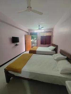 a bedroom with two beds and a tv on the wall at JP Residency, near to Isha, Adhiyogi & Karunya in Alāndurai
