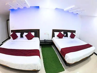 two beds in a room with red pillows at The Travellers Nest in Ooty