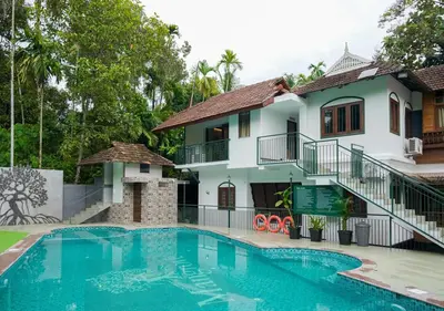 a villa with a swimming pool in front of a house at Mangrove Heritage Home, Chendamangalam in Cochin