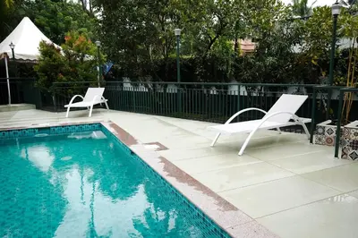 a swimming pool with two white chairs next to a white fence at Mangrove Heritage Home, Chendamangalam in Cochin