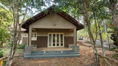 a small house with a porch in the woods at Diya's Estate Stay in Thamarassery
