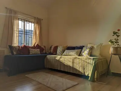a living room with a couch and a window at Bagaan - Tea Plantation Stay, Ooty in Aruvankadu