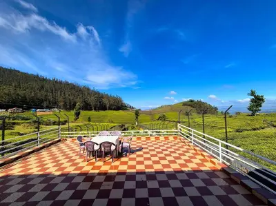 a patio with a table and chairs and a field at Bagaan - Tea Plantation Stay, Ooty in Aruvankadu