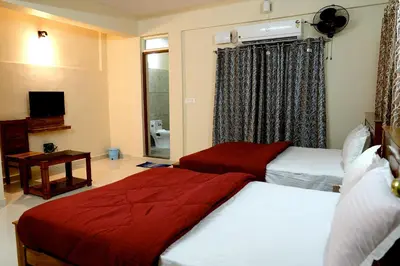 a hotel room with two beds and a television at HILL PALACE RESIDENCY COORG in Virajpet