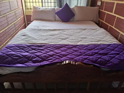 a bed with purple and white sheets and pillows at Royal homes a5 in Kushālnagar