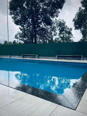 a swimming pool with two benches and blue water at Rivera Holiday Home in Vythiri