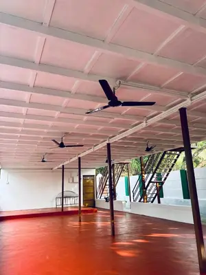 a room with two ceiling fans and a red floor at Greene Villa in Palakkad