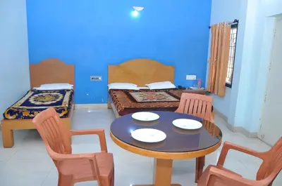a room with a table and chairs and a bed at Vinayaka Deluxe Lodge in Kushālnagar