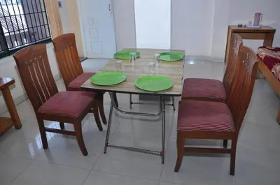 a dining room table with green plates and chairs at Vinayaka Deluxe Lodge in Kushālnagar