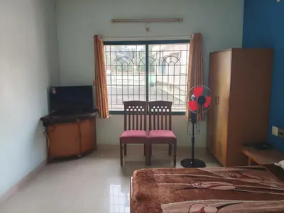 a bedroom with a table and a chair and a window at Vinayaka Deluxe Lodge in Kushālnagar