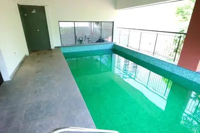 a swimming pool with green water in a house at The Nova Heights in Kozhikode