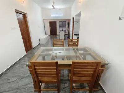 a dining room with a glass table and chairs at Avian Oasis Homestay in Thattakād