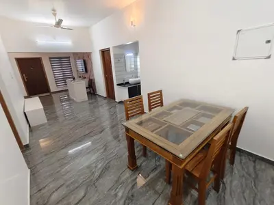 a dining room with a table and chairs and a kitchen at Avian Oasis Homestay in Thattakād