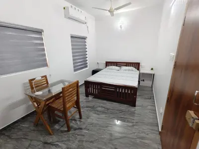 a bedroom with a bed and a table and chairs at Avian Oasis Homestay in Thattakād