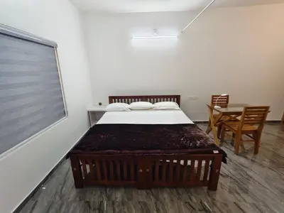 a bedroom with a bed and a table with chairs at Avian Oasis Homestay in Thattakād