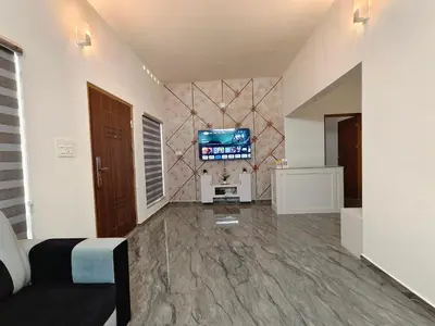 a living room with a couch and a tv on a wall at Avian Oasis Homestay in Thattakād