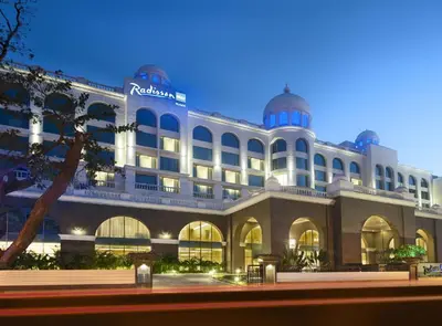 a large building with aidium hotel at night at Radisson Blu Plaza Hotel Mysore in Mysore