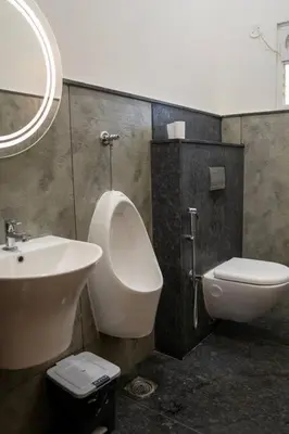 a bathroom with a sink and a urinal and a toilet at Bumblebee - The Penthouse in Mysore