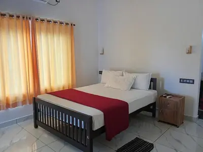 a bedroom with a bed with a red blanket at Appu's Nido in Pallipuram