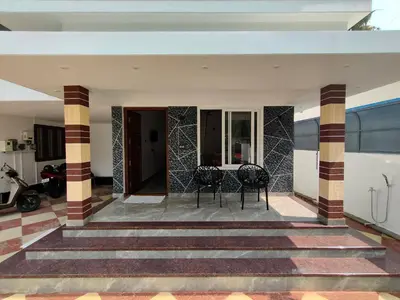 a patio with two chairs and a table in a house at Coastal Den Homestay in Pallipuram