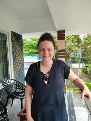 a woman in a black shirt standing on a porch at Coastal Den Homestay in Pallipuram