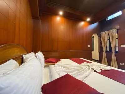 two beds in a room with wooden walls at Lakefront Home Hotel in Ooty
