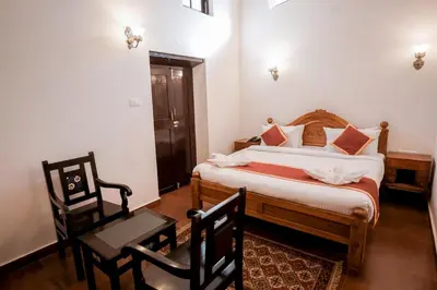 a bedroom with a bed and two chairs and a table at Lakefront Home Hotel in Ooty