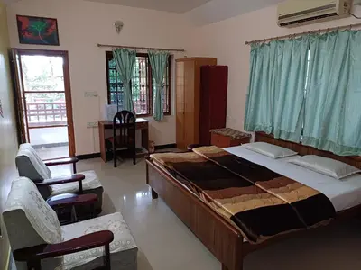 a bedroom with a large bed and two chairs at Unwind @ Serene Retreat in Palakkad