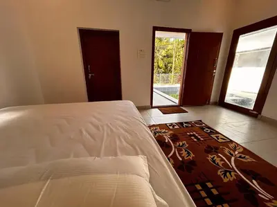 a bedroom with a bed and a room with a door at Nila Farms - Farm stay with a unique swimming Pool in Attappādi