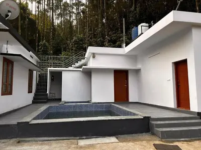 a white house with a swimming pool in the courtyard at Nila Farms - Farm stay with a unique swimming Pool in Attappādi