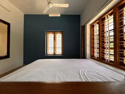 a bedroom with a large bed and a blue wall at Nila Farms - Farm stay with a unique swimming Pool in Attappādi