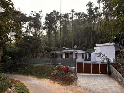 a house with a fence next to a dirt road at Nila Farms - Farm stay with a unique swimming Pool in Attappādi
