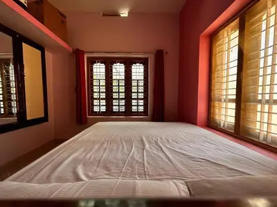 a large bed in a room with two windows at Nila Farms - Farm stay with a unique swimming Pool in Attappādi
