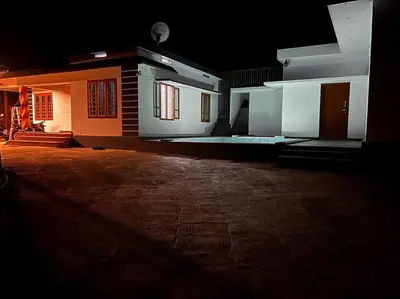 a dark room with a house with lights on at Nila Farms - Farm stay with a unique swimming Pool in Attappādi
