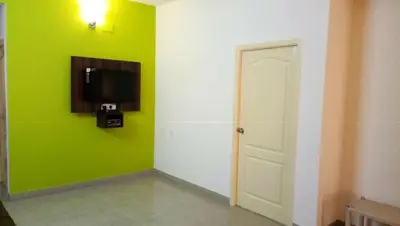 a room with a green wall with a tv and a door at ThulasiRams Service Apartments in Coimbatore