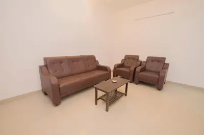 two leather couches and a coffee table in a room at ThulasiRams Service Apartments in Coimbatore