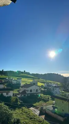 a view of a town with the sun in the sky at Amarah Homestay in Ooty