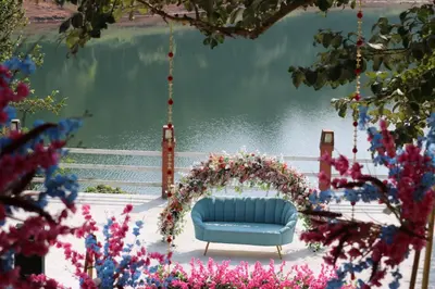 a blue couch sitting on a swing by the water at Wayanad Silverwoods Forest Resort & Spa in Padinjarathara