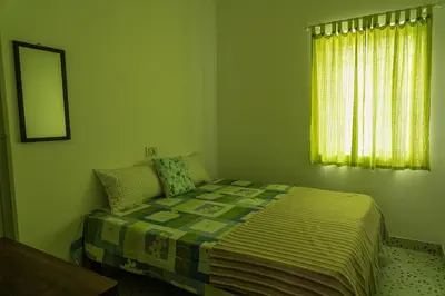 a green bedroom with a bed and a window at Maya Homez - Coimbatore in Coimbatore