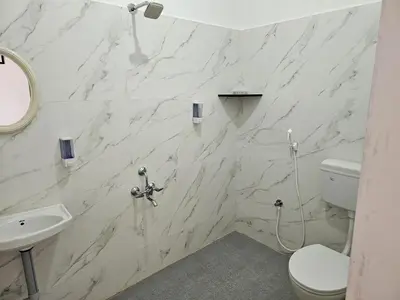a bathroom with a white marble wall at Maya Homez - Coimbatore in Coimbatore