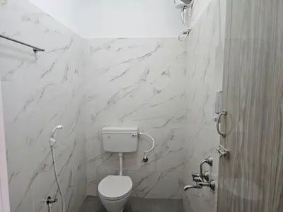 a bathroom with a toilet and a marble wall at Maya Homez - Coimbatore in Coimbatore