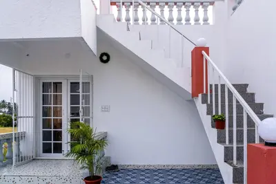 a white house with stairs and potted plants at Maya Homez - Coimbatore in Coimbatore