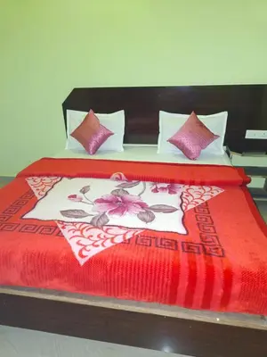 a bed with a red blanket and pink pillows at Pavithra cottage munnar in Munnar
