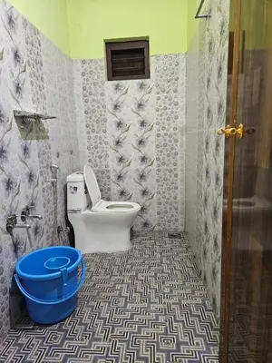a bathroom with a toilet and a blue bucket at Pavithra cottage munnar in Munnar