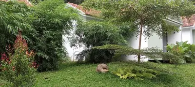 a garden of a house with trees and a rock at Le Vista Resort in Sultan Bathery