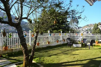 a white fence with a tree in a yard at Serene Hills in Ooty